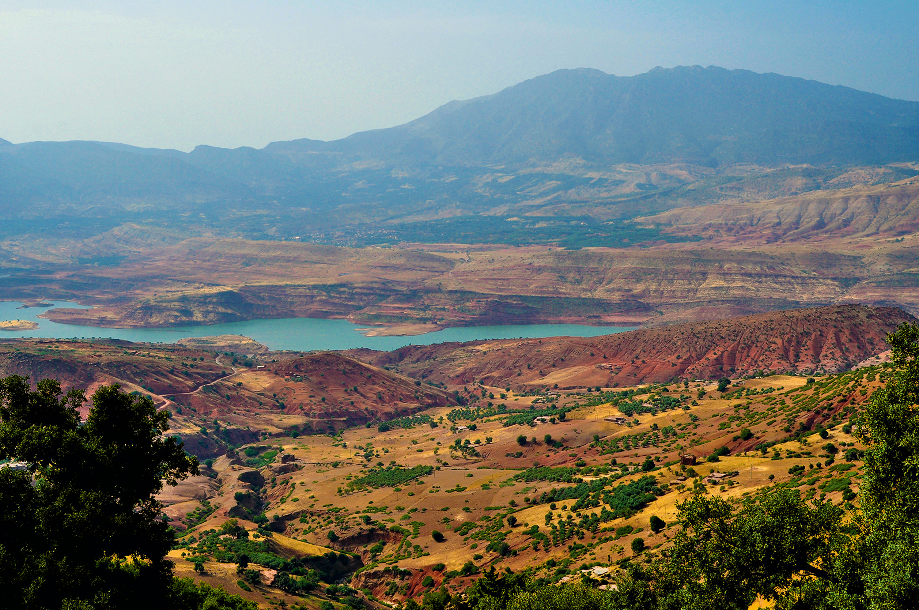 A valley with a turquoise reservoir stretches beneath mountains in Morocco