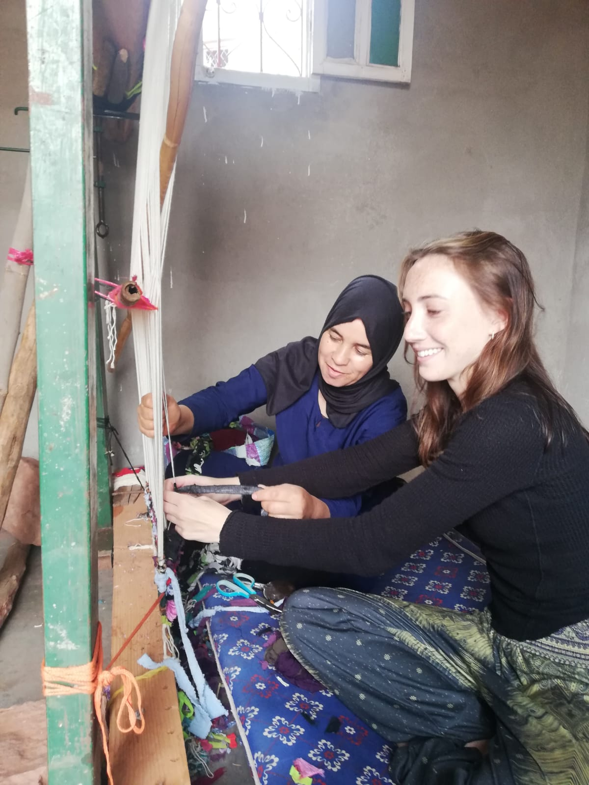 A student learns traditional loom weaving from a local artisan