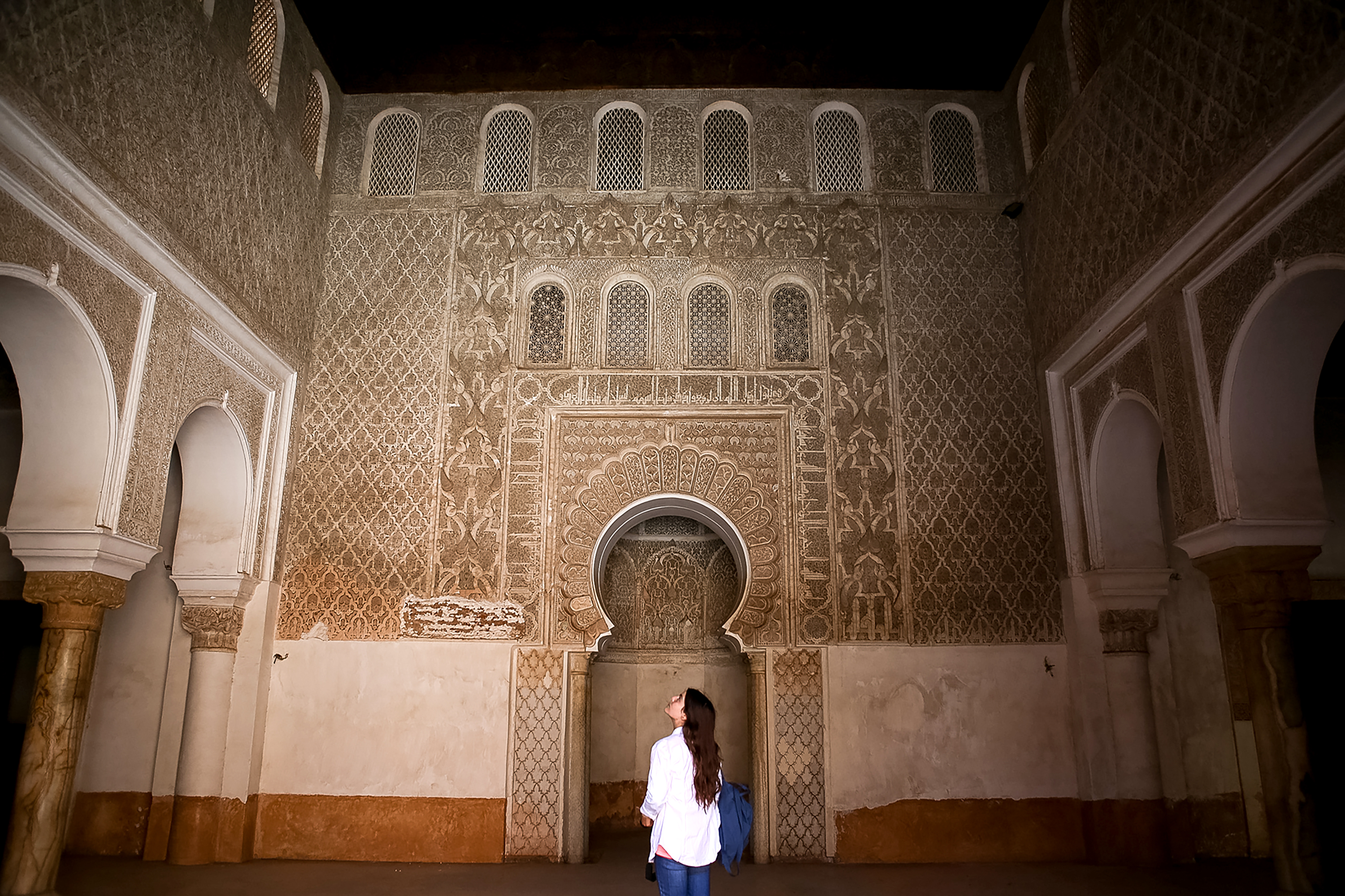 A student admires the ornate carved plasterwork of a Moroccan medersa doorway