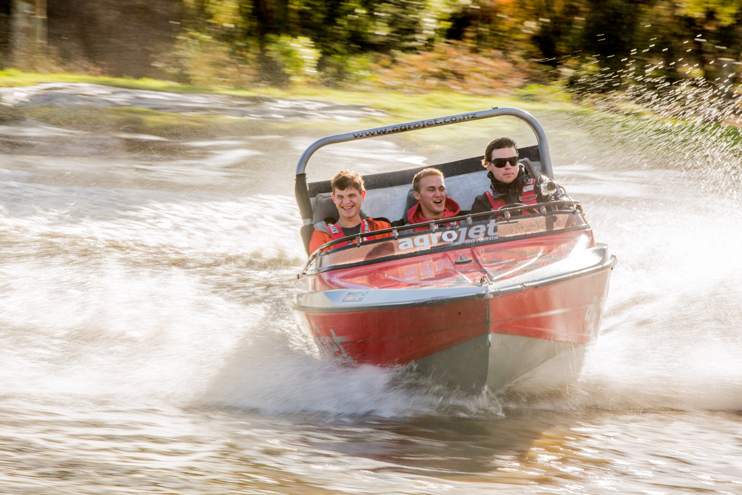 Students ride a jet boat as it sprays water across a lake in New Zealand