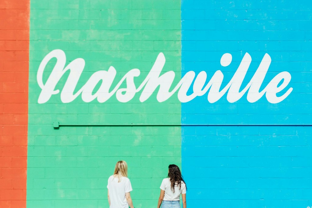Picture of 2 girls staring at wall that has the word "Nashville" painted over it. Fun facts about Nashville