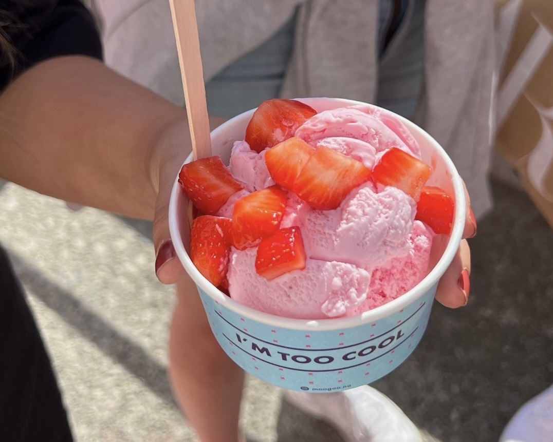 A student holds a cup of pink ice cream topped with fresh strawberries