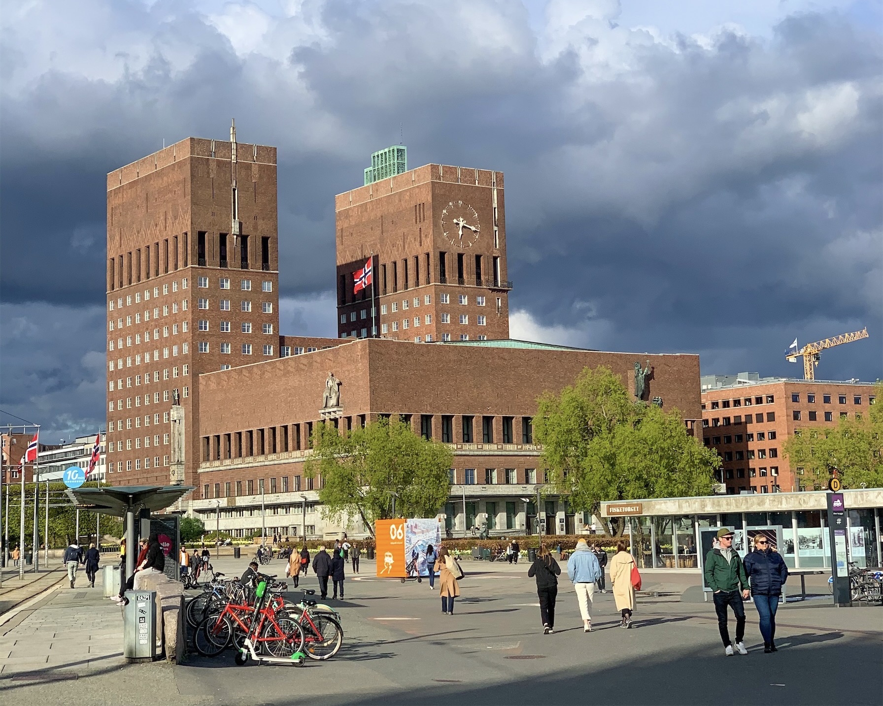 Students pause in the plaza beneath Oslo City Hall's twin brick towers, past parked bicycles