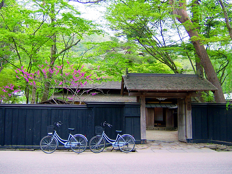 Bicycles parked outside a wooden gate at a traditional Japanese samurai house