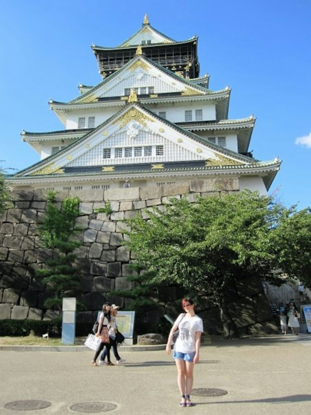 A girl poses for the camera in front of Osaka Castle. Learn some fun facts about Osaka.
