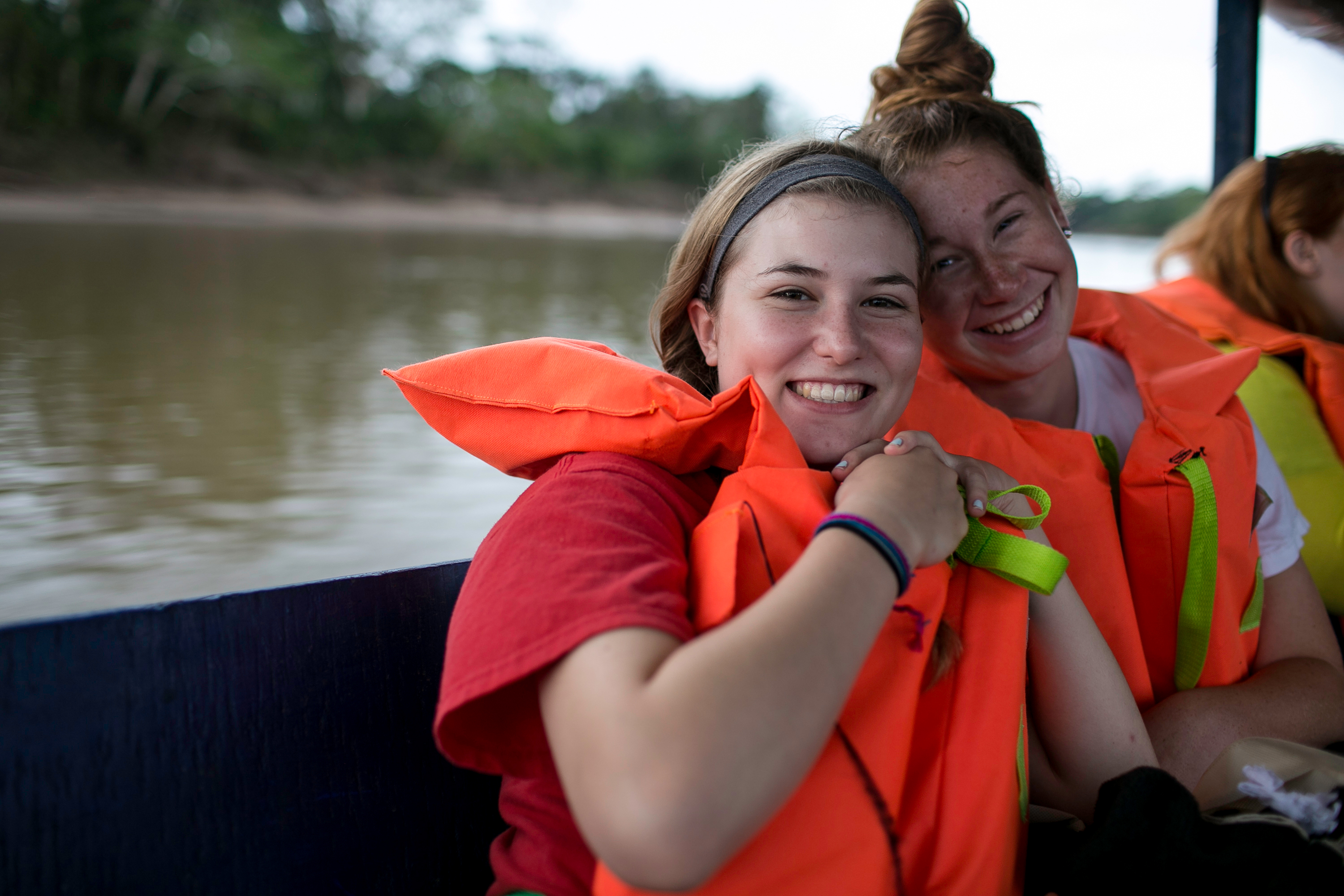 Students with life vests on a boat posing for the camera.