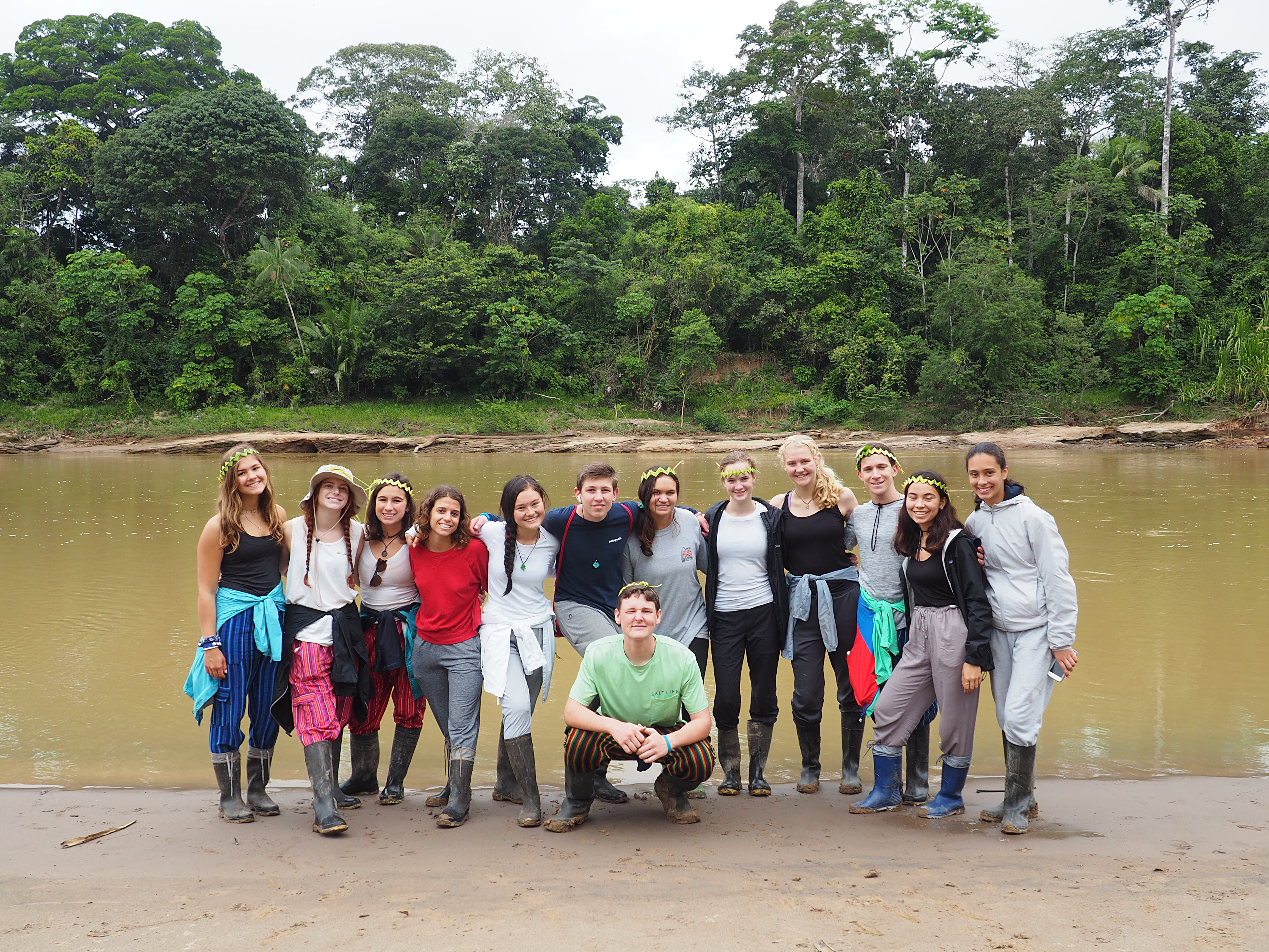 Students posing standing in front of a lake in Peru with trees in the background.
