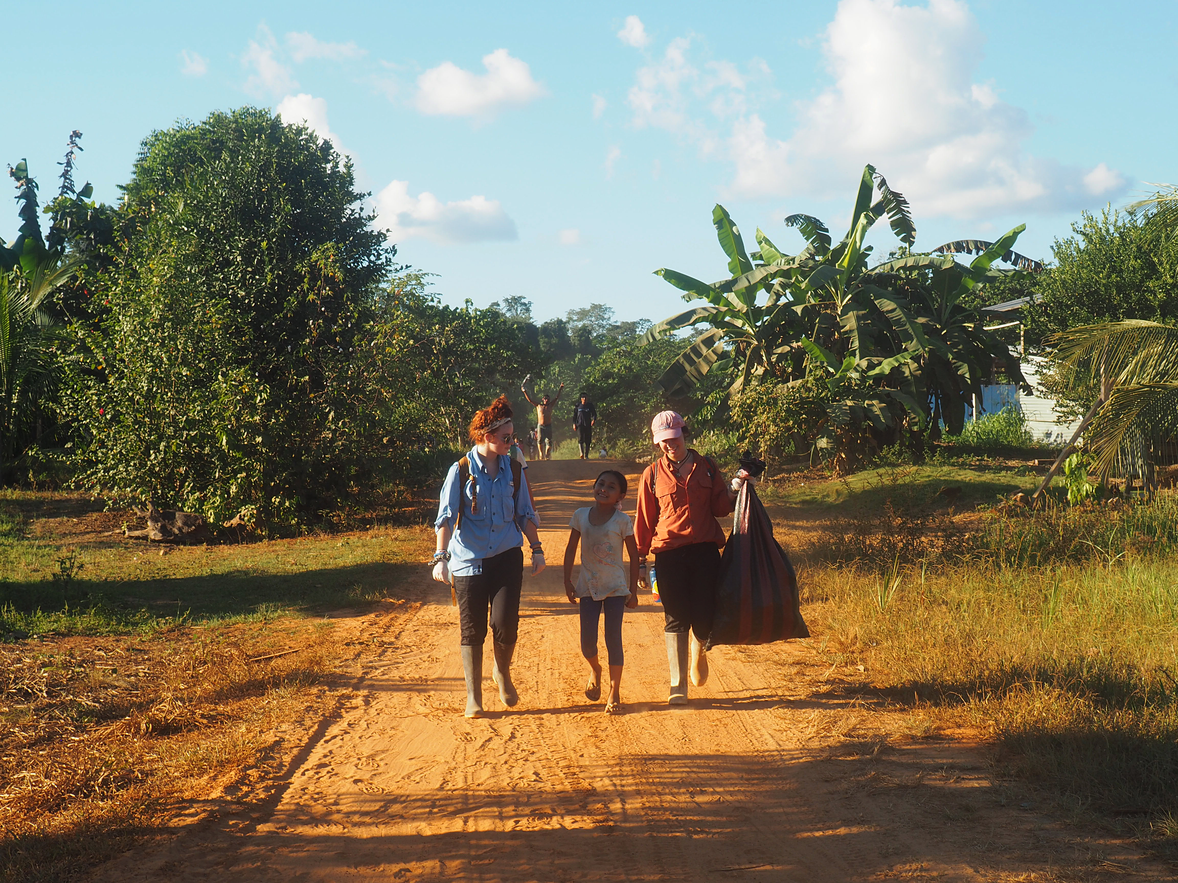2 adults and 1 child walking together in Peru with one woman holding a bag.