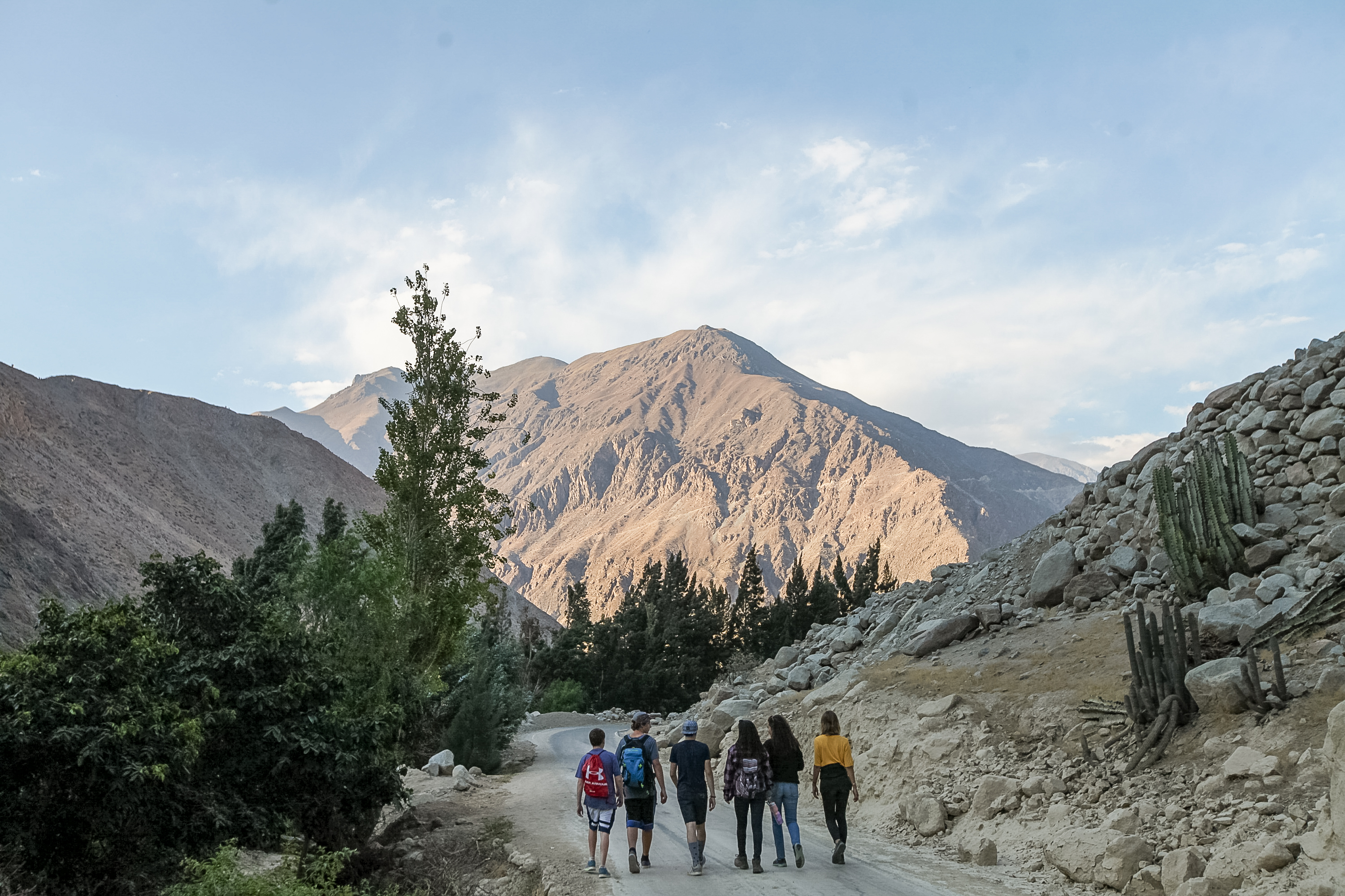 Students walk along a dirt road toward Andean peaks in the Sacred Valley
