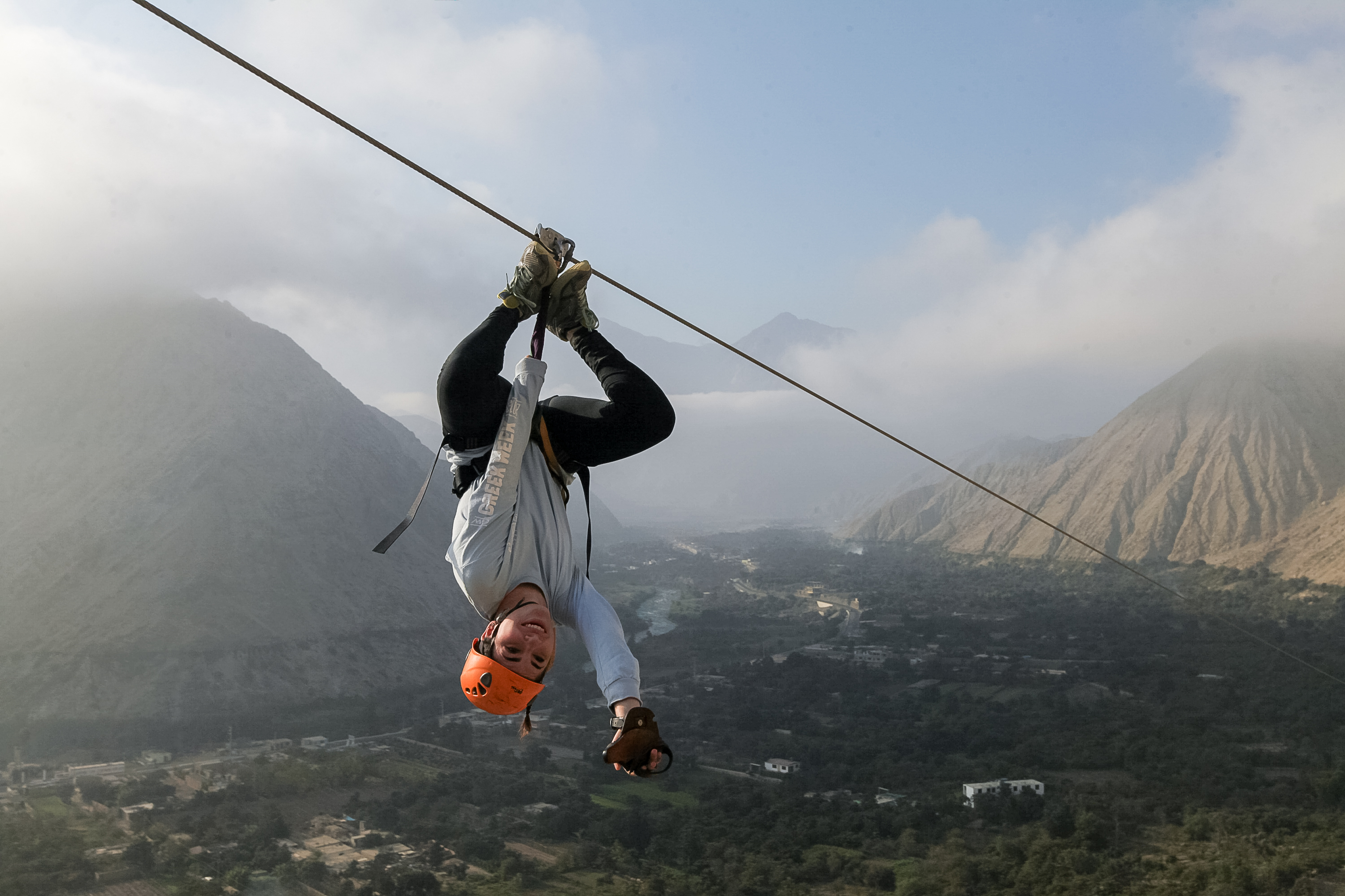 A student rides a zipline upside down over a valley in the Andes in Peru