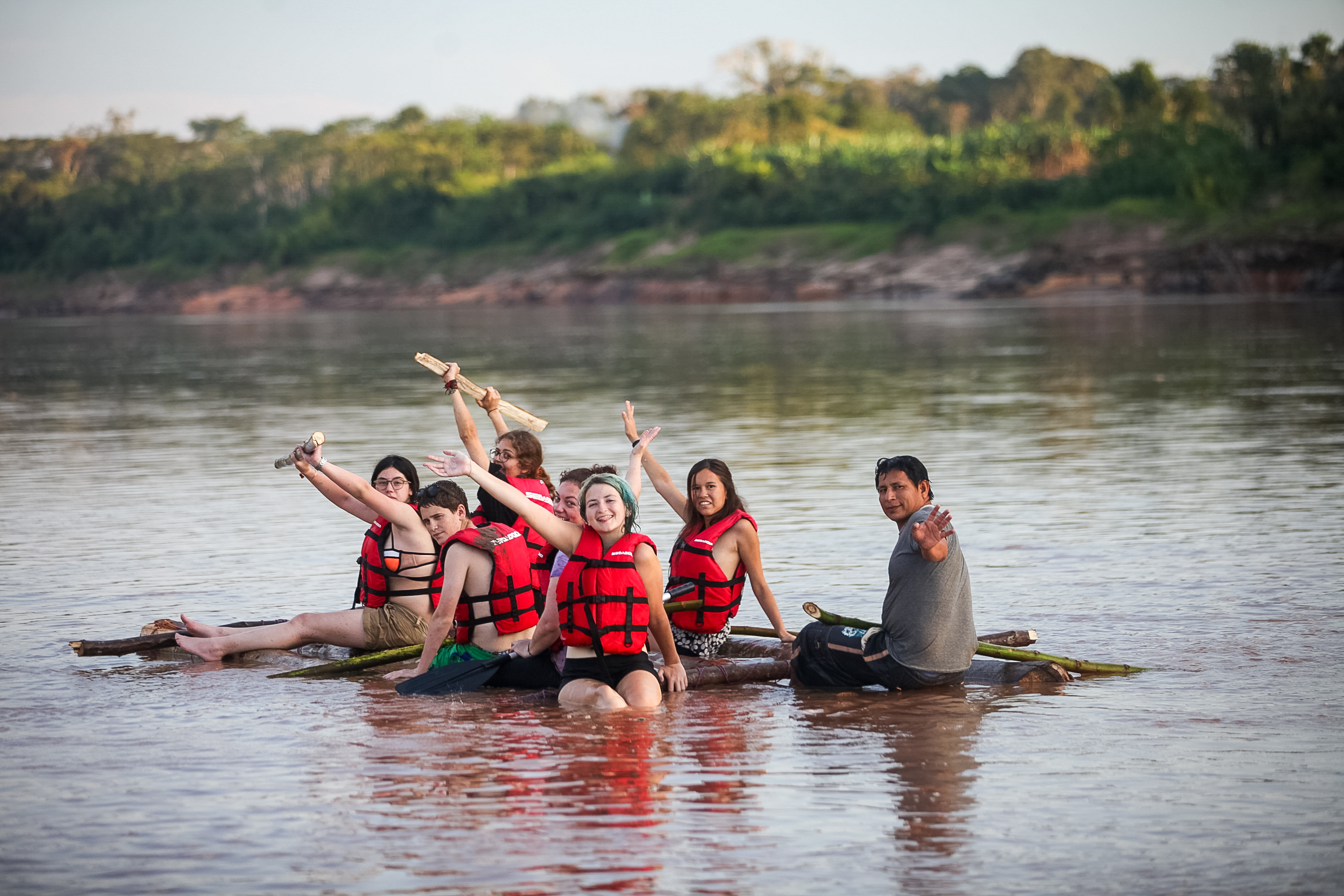Students on a raft in Peru with trees in the background.