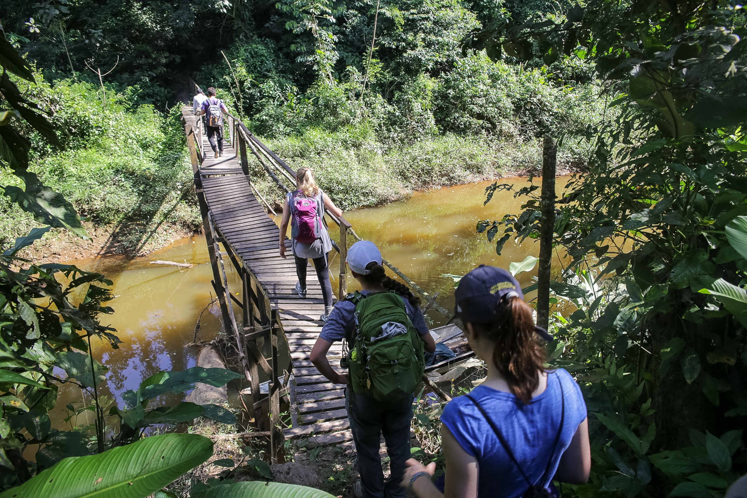 Students working across bridge which goes over lake and trees in the background.