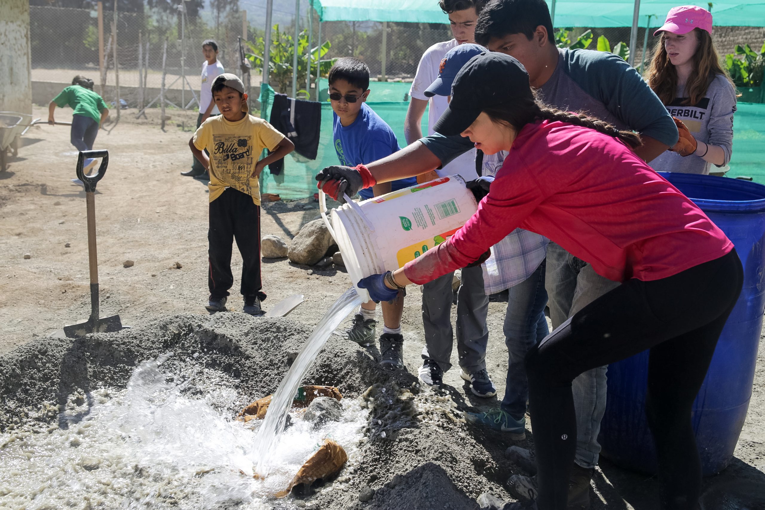Students pouring something to pit while helping in community service project in Peru.