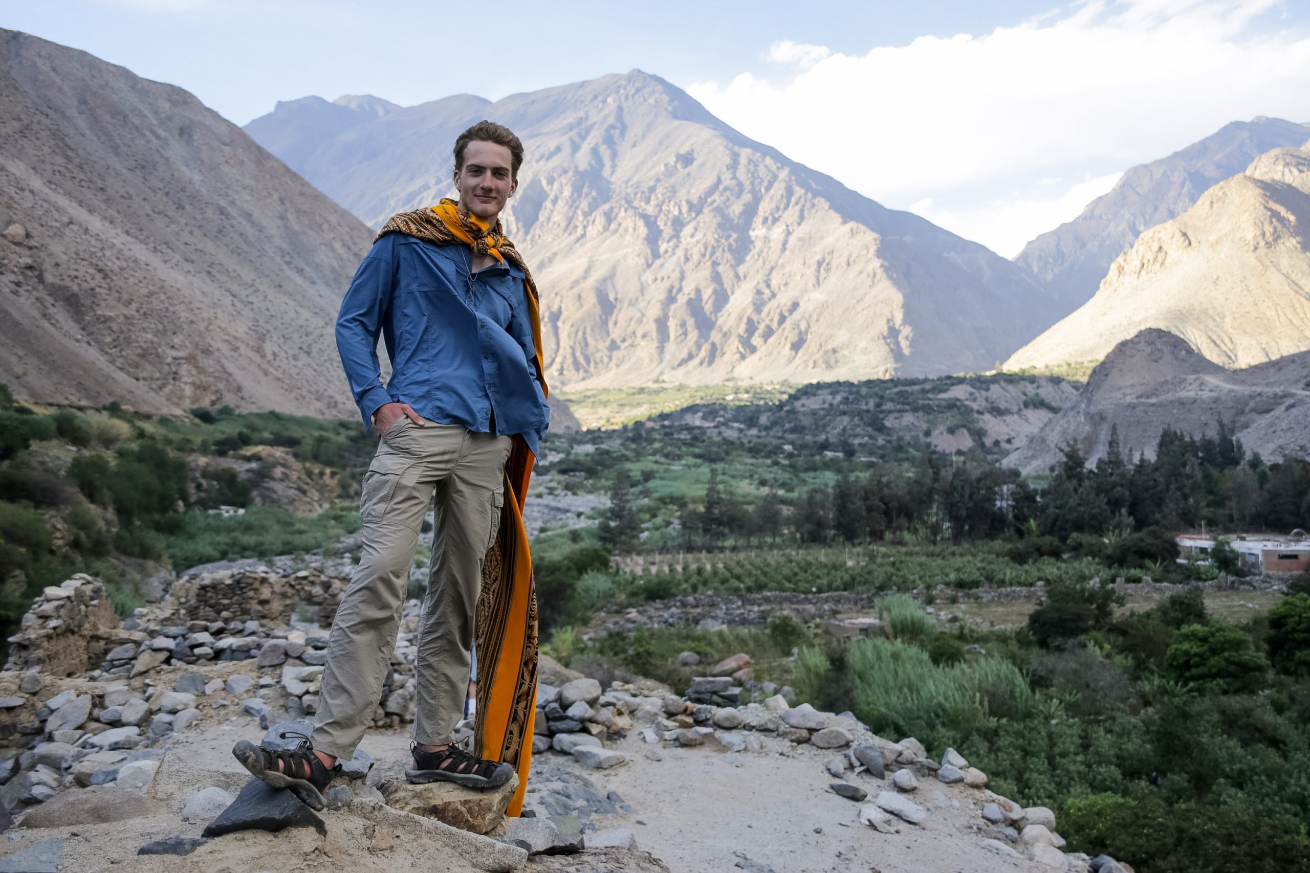 Student travelers stand on a rocky overlook above the Andean valley