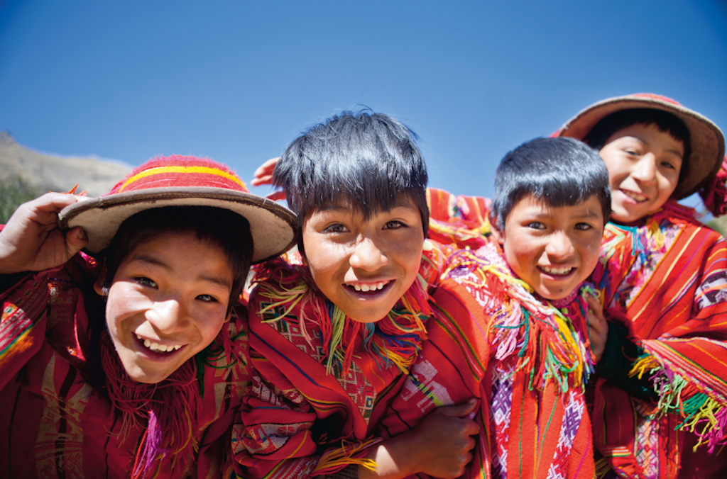 Children smiling in traditional clothing during a Rustic Pathways volunteer abroad in South America program focused on cultural exchange and education in Peru.