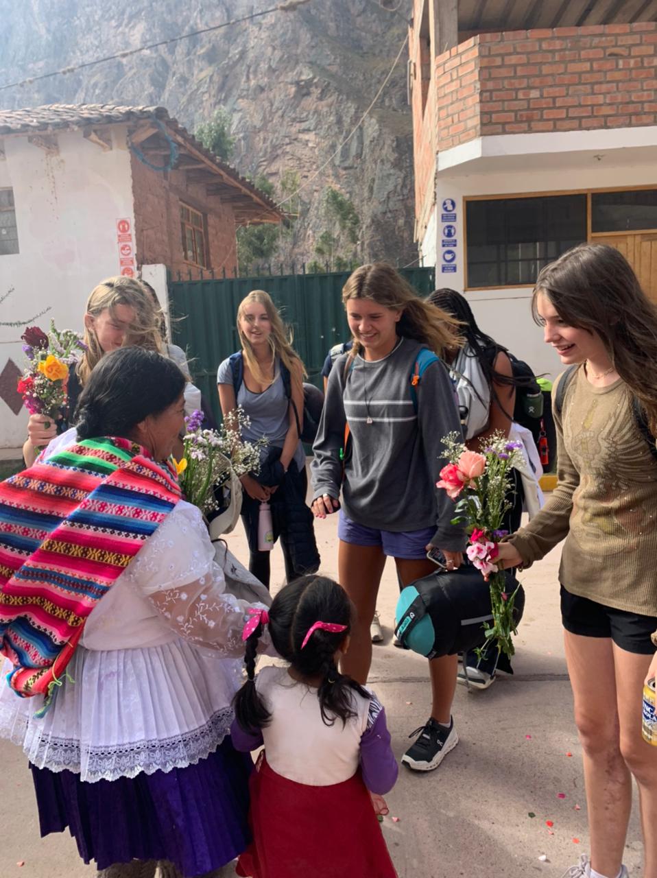 Students exchange flowers with local villagers on a village street in the Sacred Valley in Peru