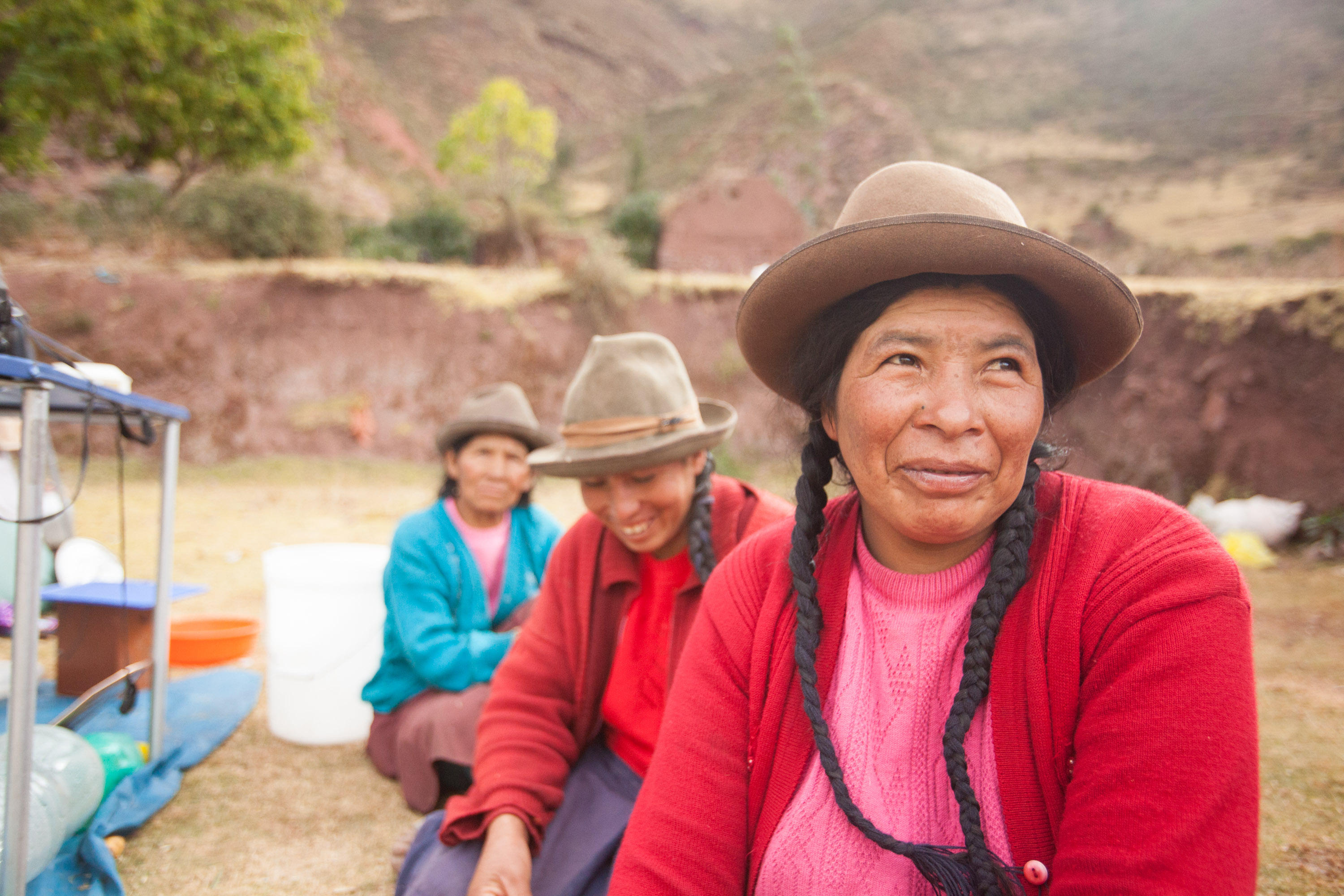 Andean women wearing traditional hats sit outdoors in the Sacred Valley