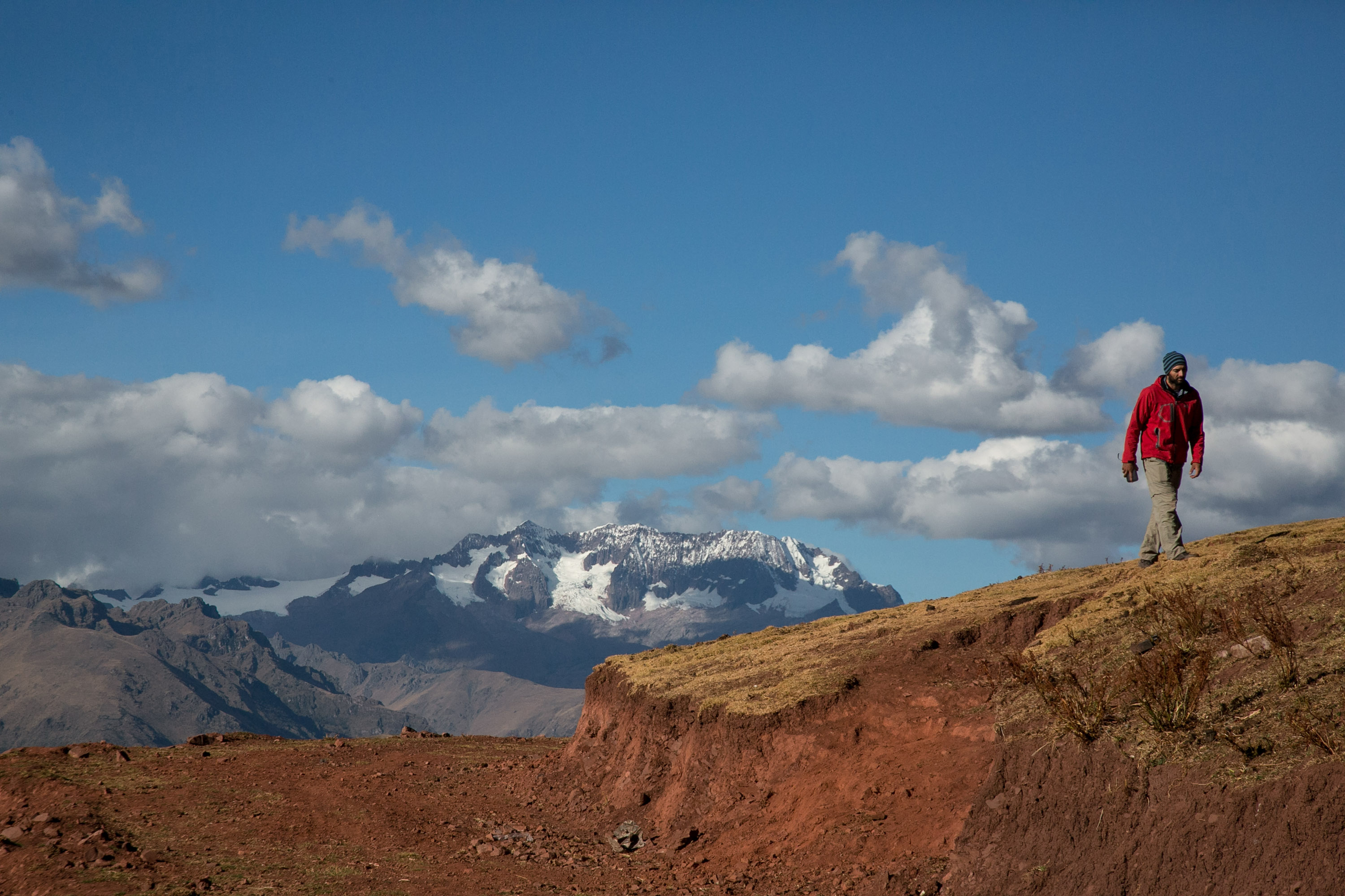 A student walks a ridge overlooking snow-capped Andes peaks