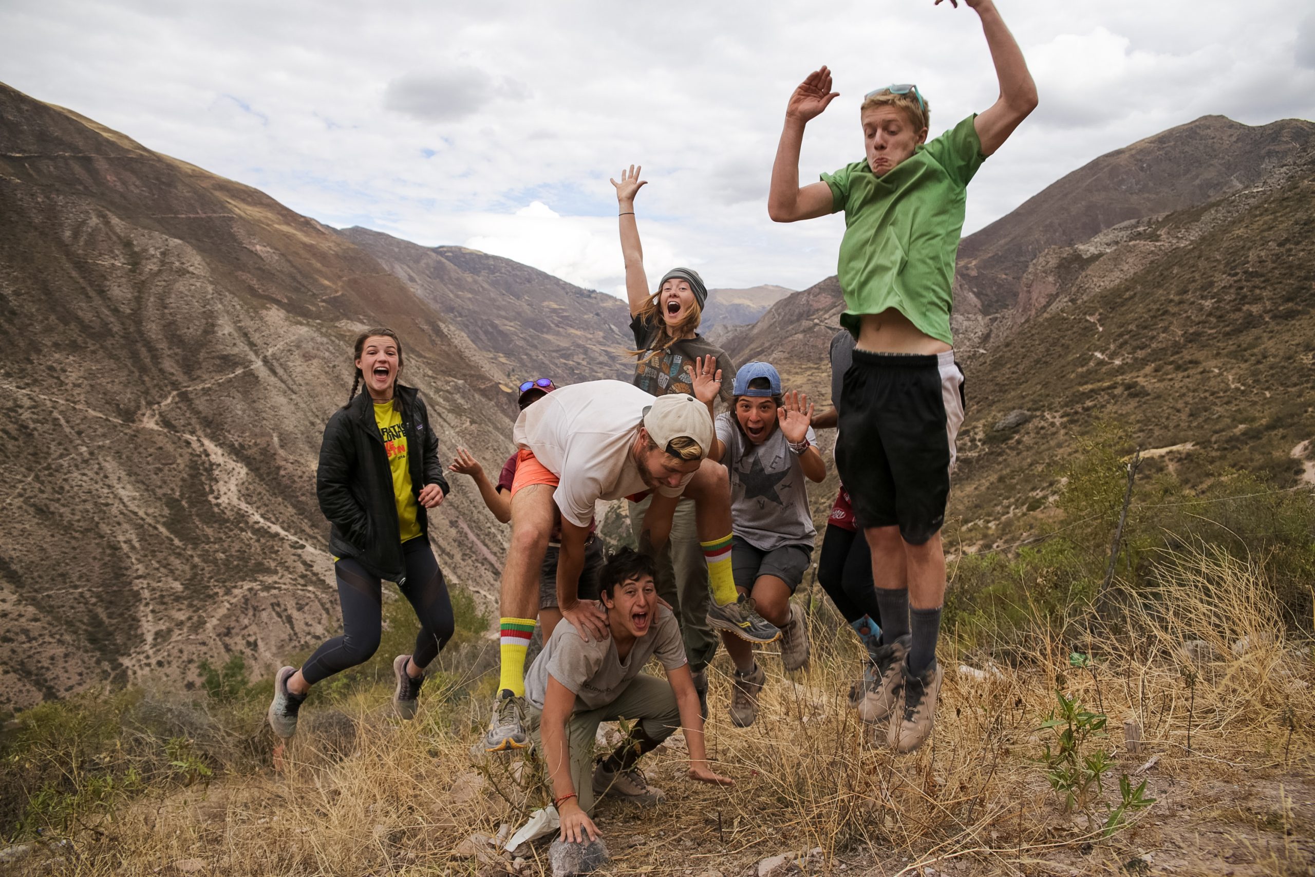 Students jump and cheer on a mountainside trail in the Andes