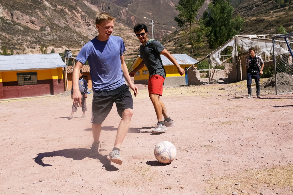 Students play pick up soccer. Mountains in the background.