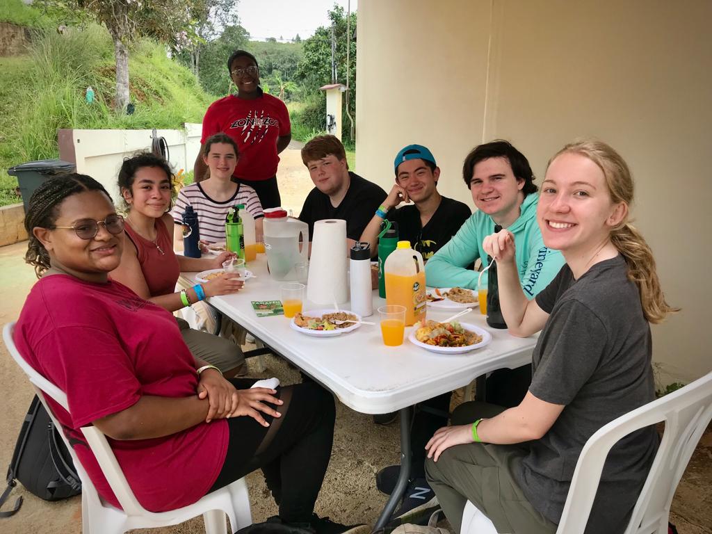 Students and hosts share a meal at a long table.