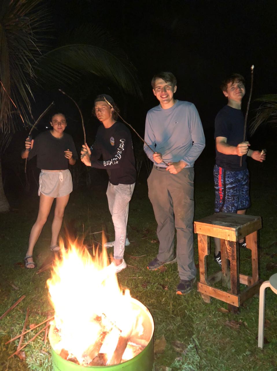 A school group around an evening bonfire on the beach.