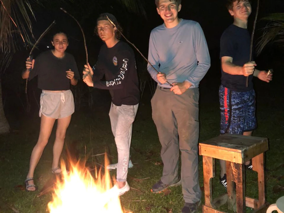 A school group around an evening bonfire on the beach.