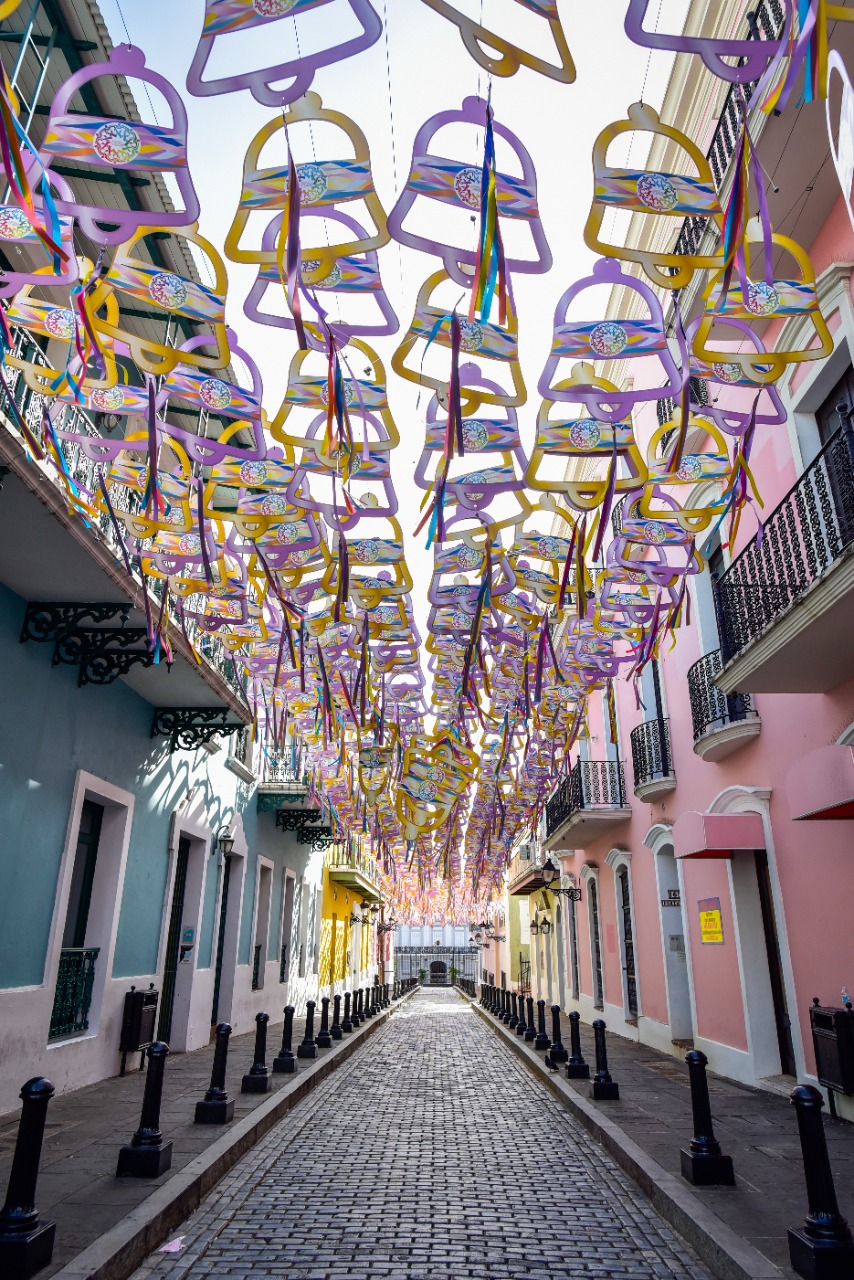 Colorful hanging decorations above a colonial street in Old San Juan.