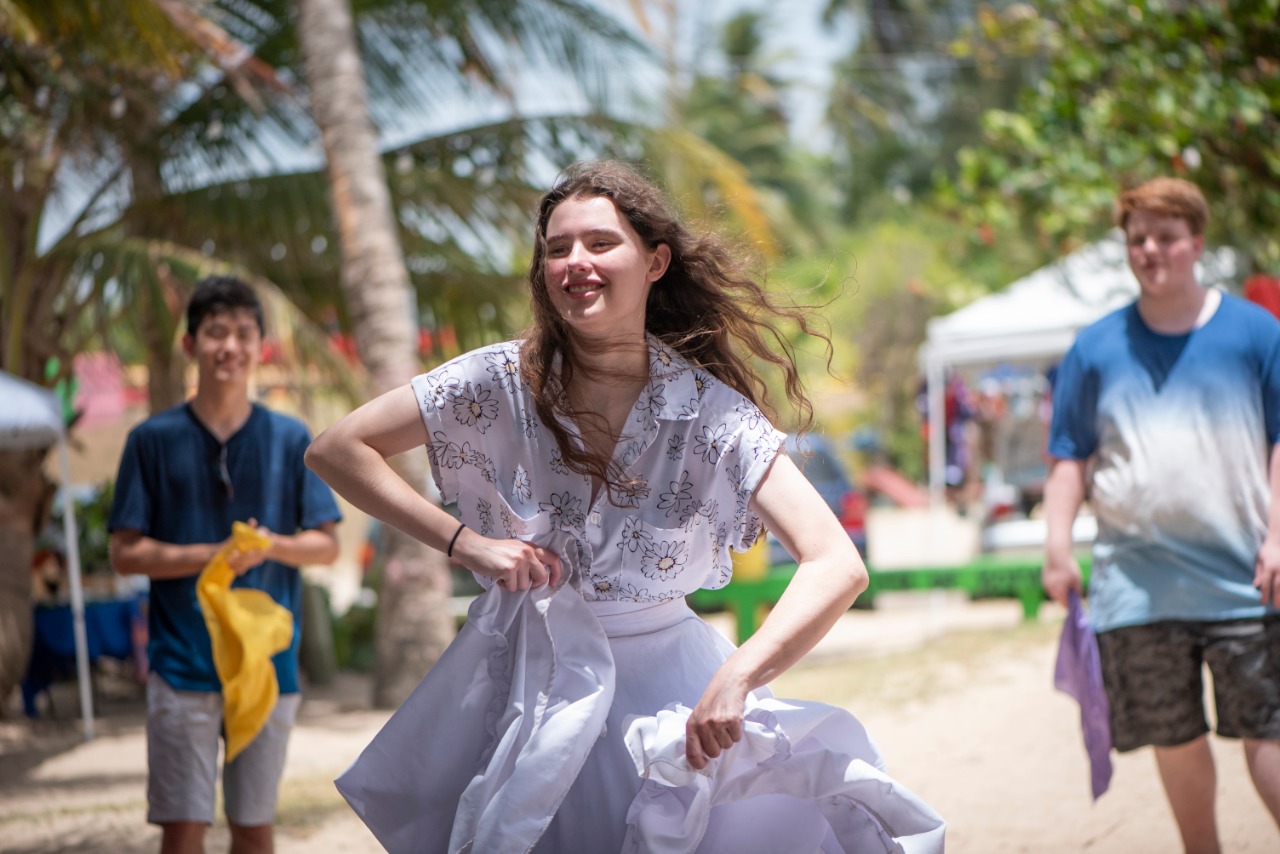 A student twirls in a skirt on a palm-lined path in Puerto Rico while others walk nearby