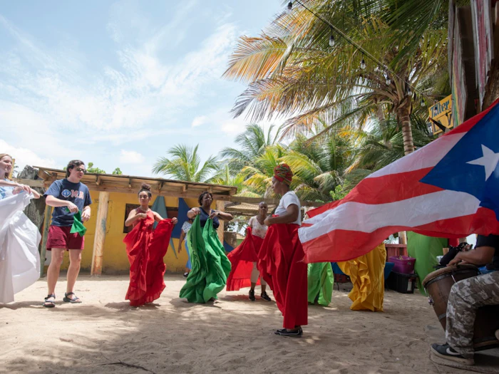 Bomba dancers in red and green skirts performing in a village street.