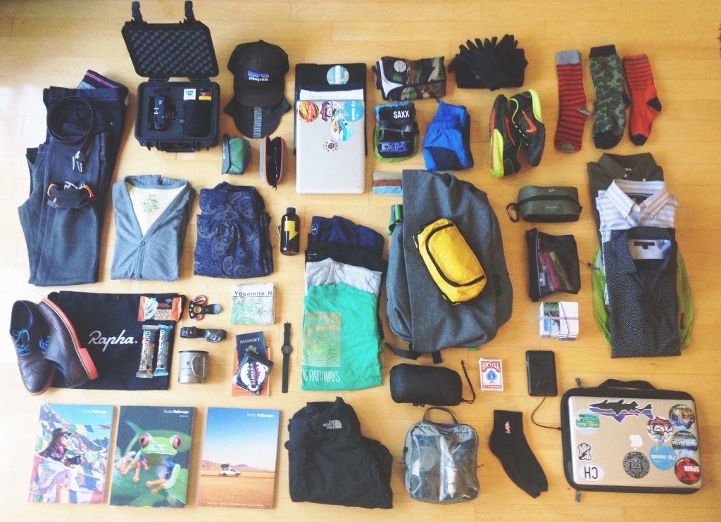 All of the essential items on our summer travel packing guide lay out on the floor, ready to be packed for the next adventure.