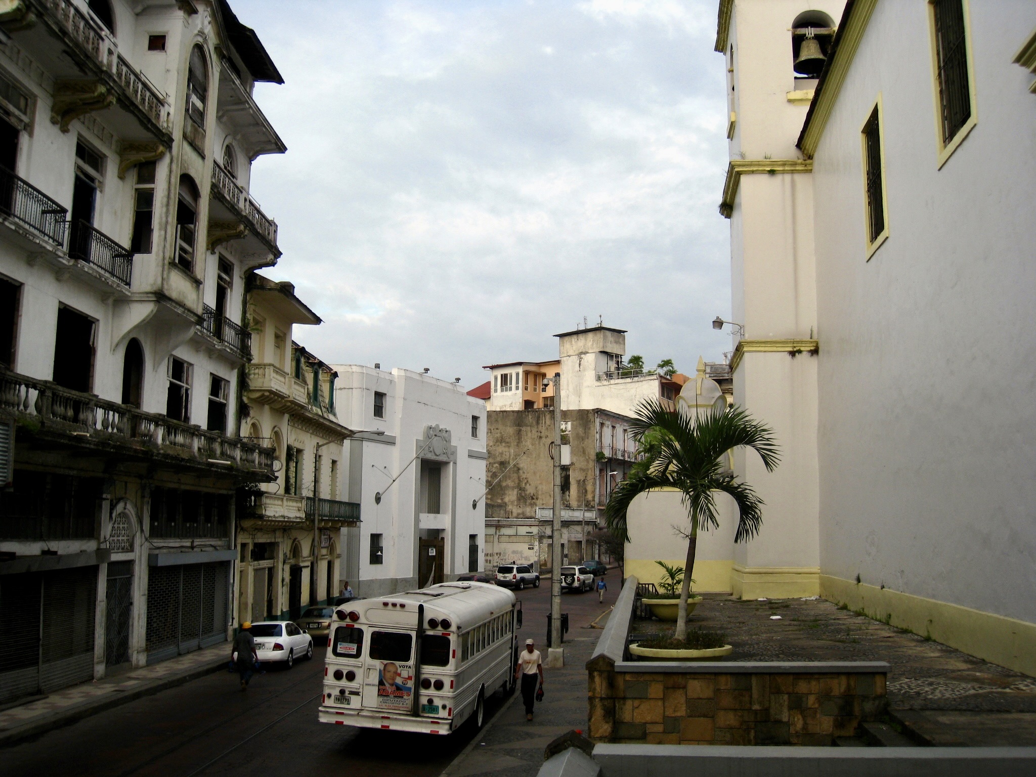 A bus and pedestrians pass colonial-era buildings on a Panama City street in Panama