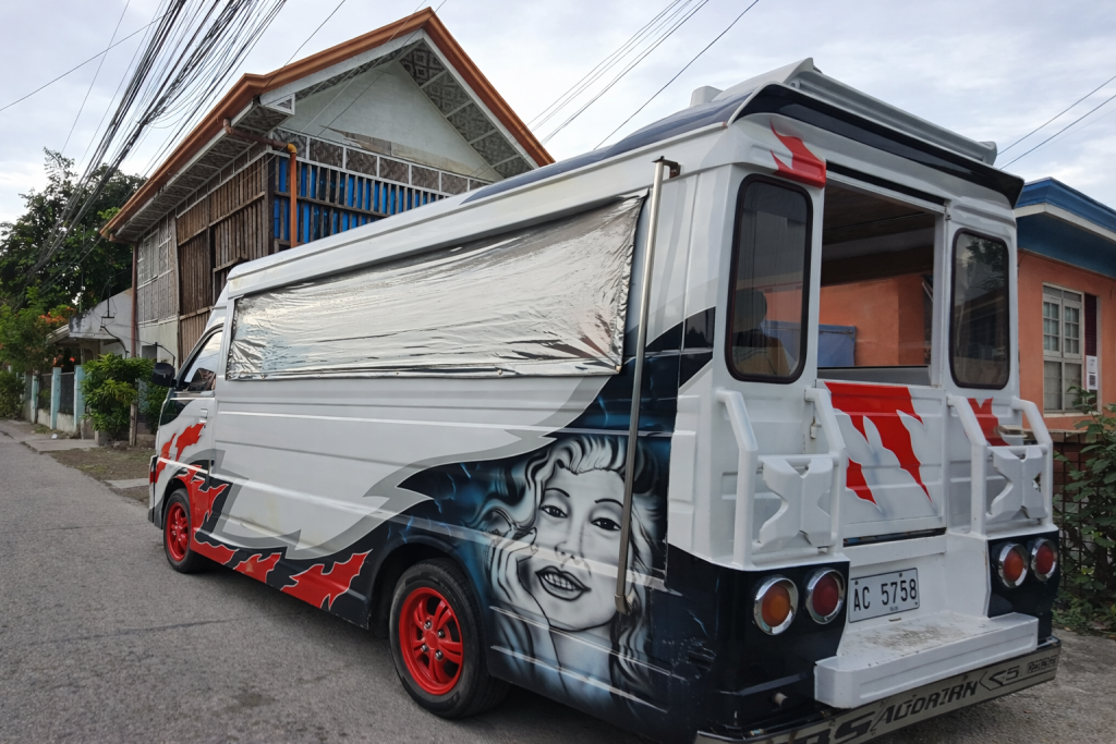 A long customized white van, or Jeepney, as they are known in the Philippines.