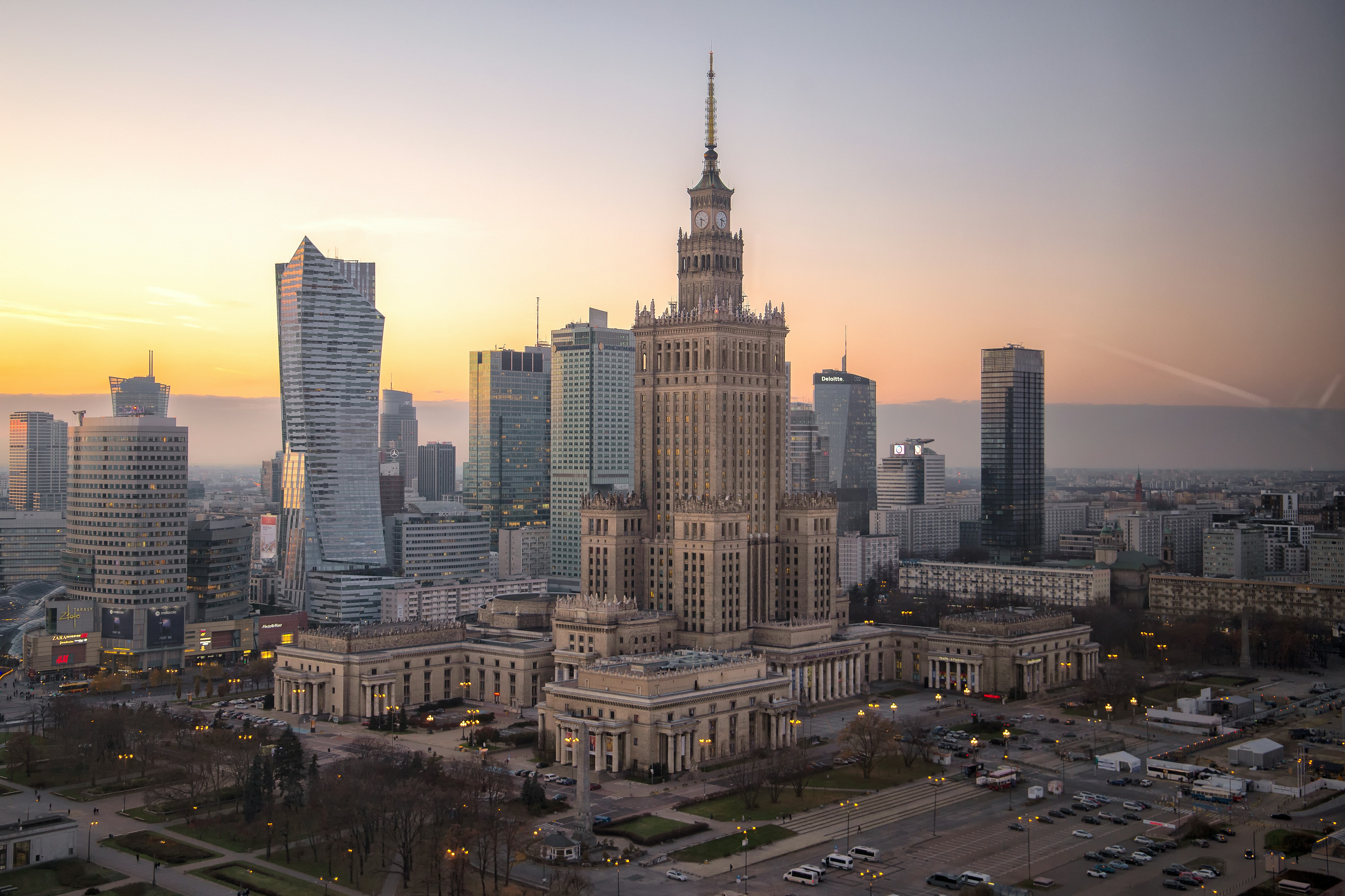 Warsaw's Palace of Culture and Science among the city's high-rise towers at sunset.