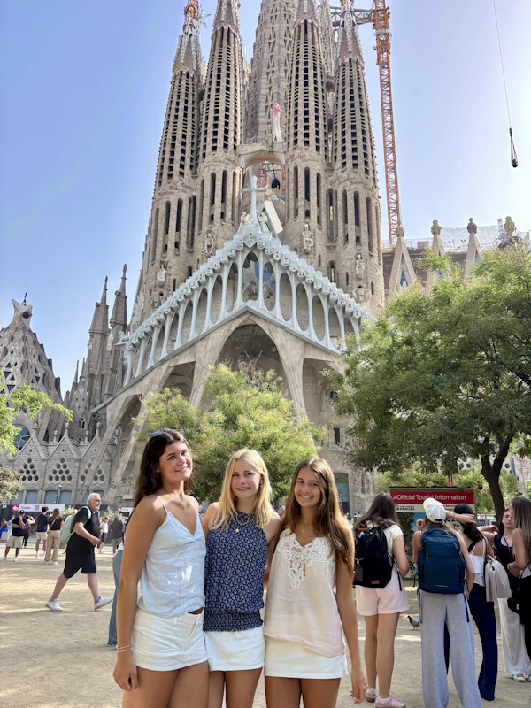 Three teen travelers stand in the plaza in front of the spires of the Sagrada Família in Barcelona