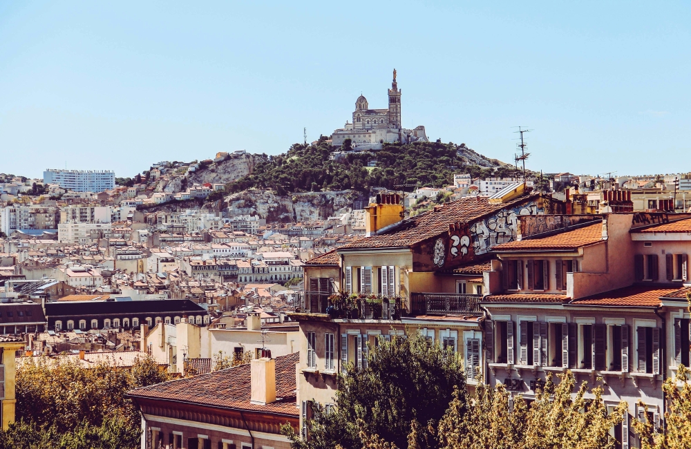 Notre-Dame de la Garde basilica crowns a hilltop above Marseille's terracotta rooftops, with the city spreading toward the sea.