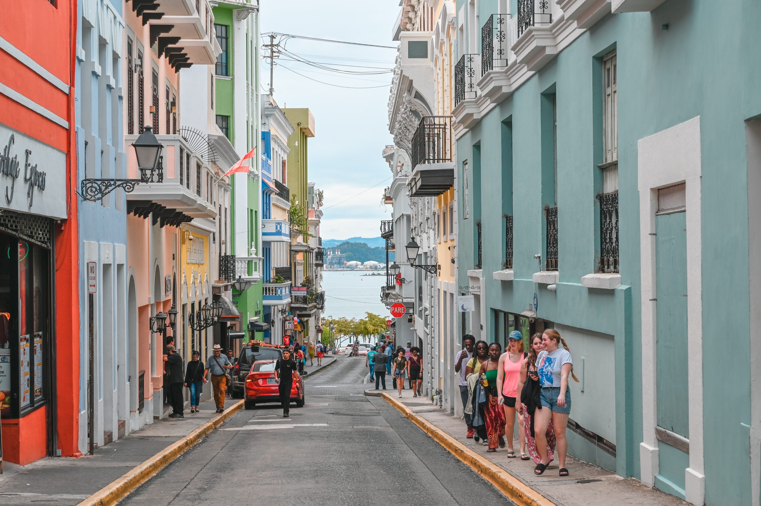Students walk down a sloped street lined with colorful buildings in Old San Juan
