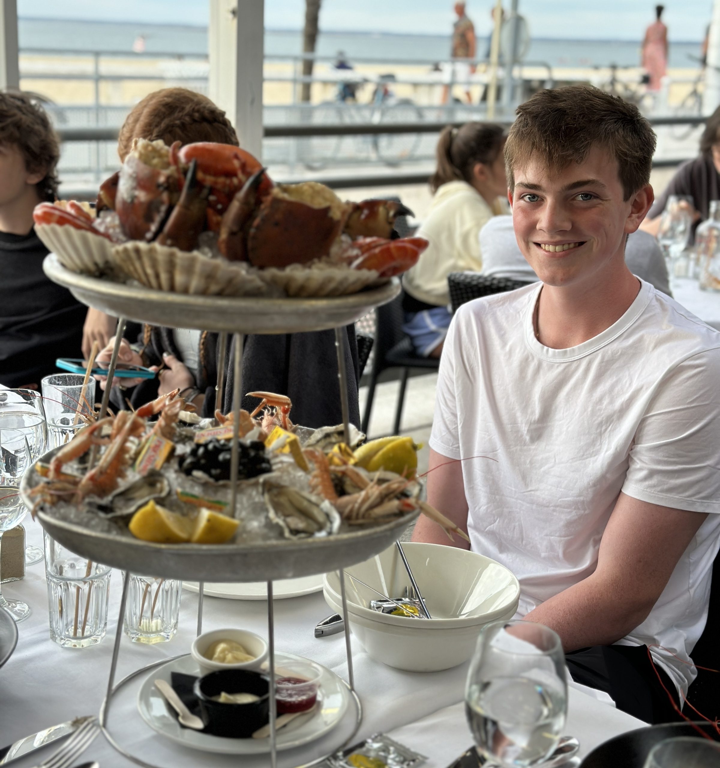 A young man at an outdoor restaurant with a seafood platter.