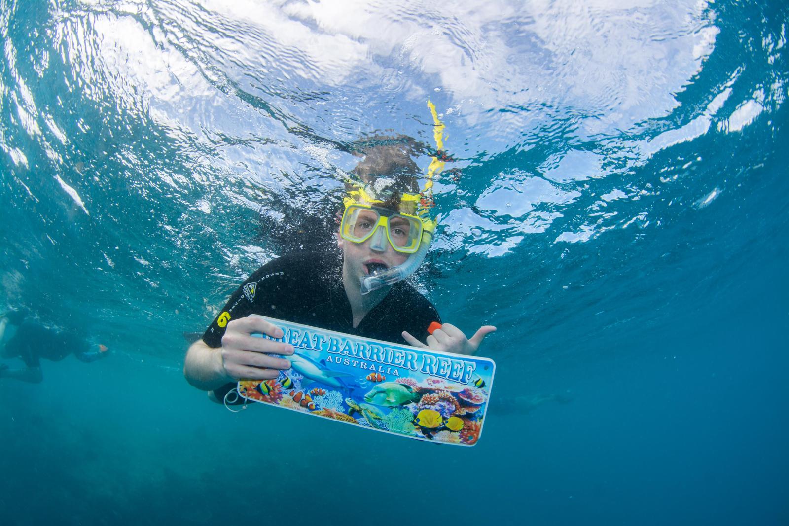 A boy holding a sign while underwater snorkeling.