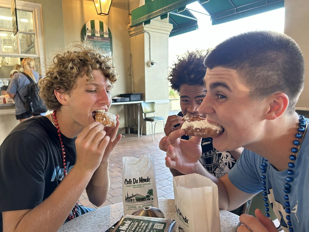 Family volunteer abroad programs teens sharing local food during a cultural immersion experience with their parents.