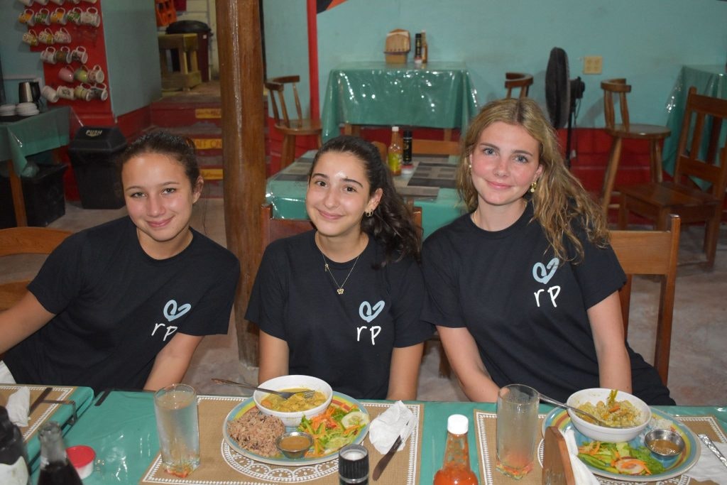 Students in Rustic Pathways t-shirts having a meal together on a summer program in Belize for high school students.