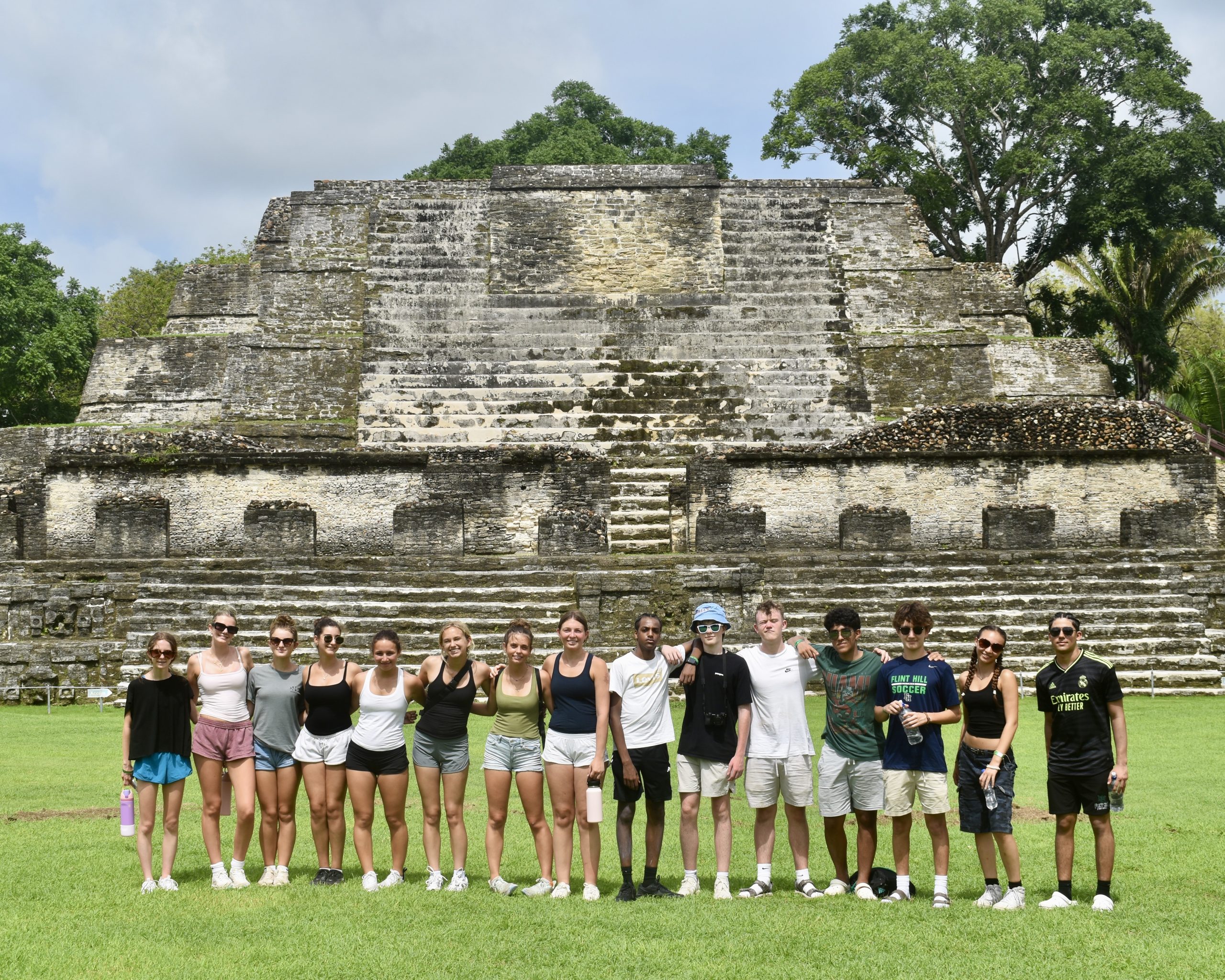 A Rustic Pathways student group lines up on the grass in front of a stepped Maya temple in Belize