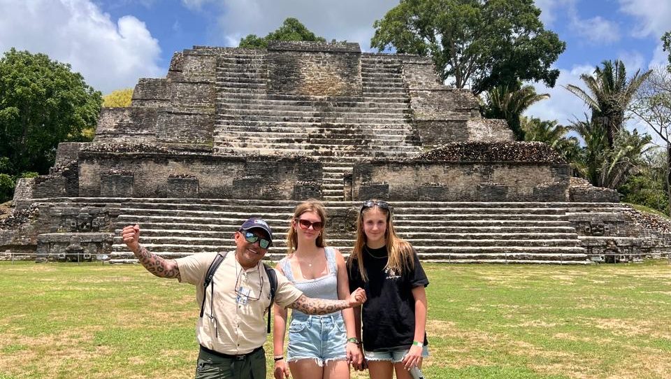 Students and a guide pose in front of a stepped Maya pyramid at Altun Ha