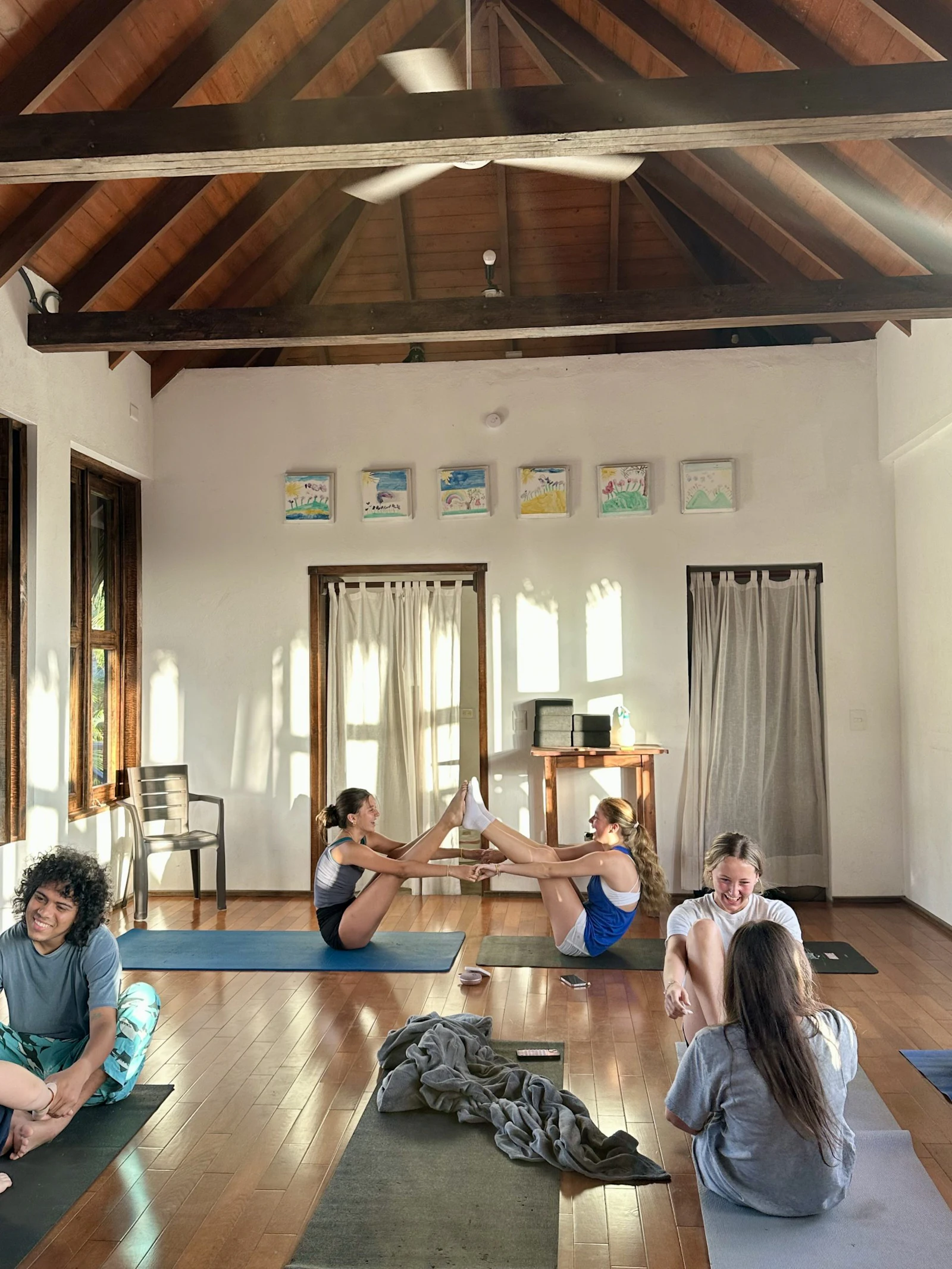 Teen travelers stretch on yoga mats in a bright room with a wooden ceiling in the Dominican Republic