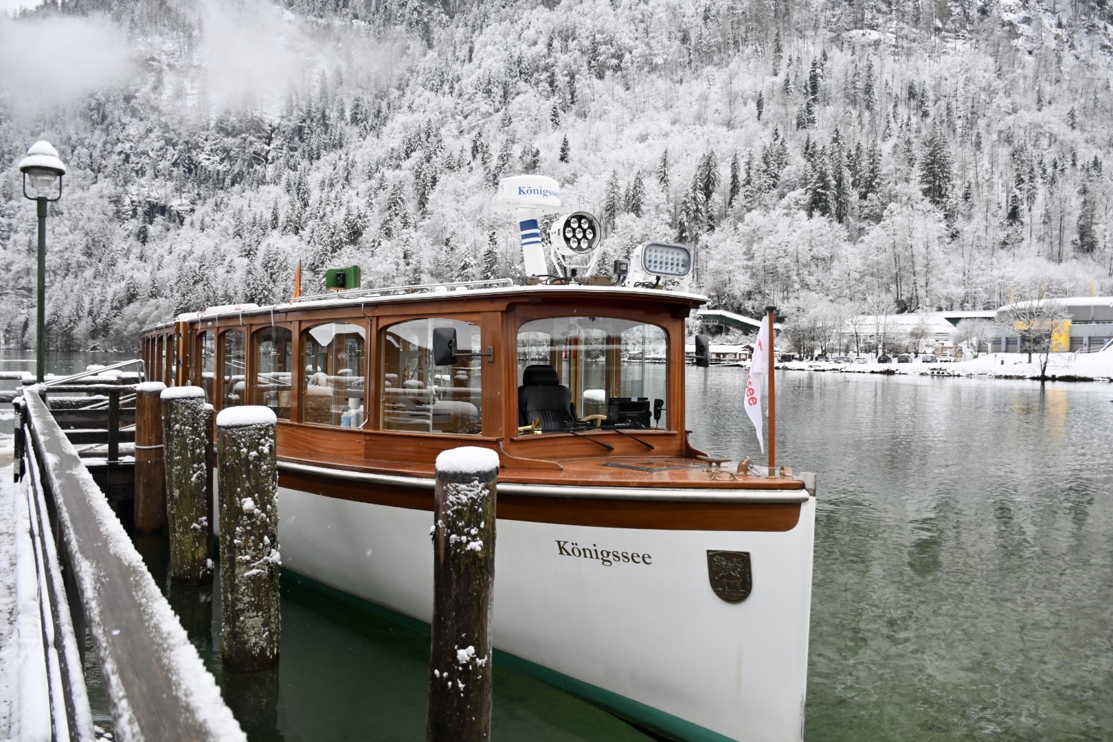 Classic wooden boat docked on the snowy shores of Lake Königssee in Bavaria, Germany, surrounded by winter forest—a favorite scenic stop for teen travel to Germany and student travel groups.