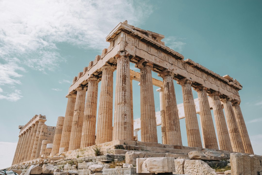 The Parthenon on the Acropolis in Athens, its Doric columns seen from below against a clear sky.