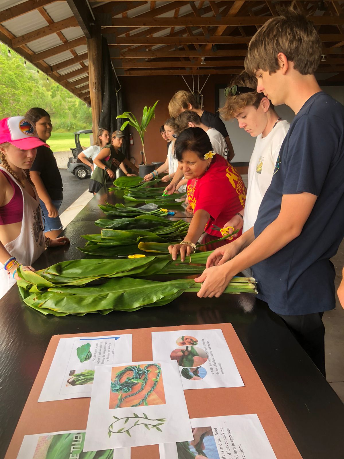Students learn lei-making with a local artisan under an open-air pavilion