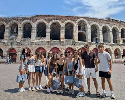 a group of students pose in front of an ancient roman amphitheater during an Italy teen tour