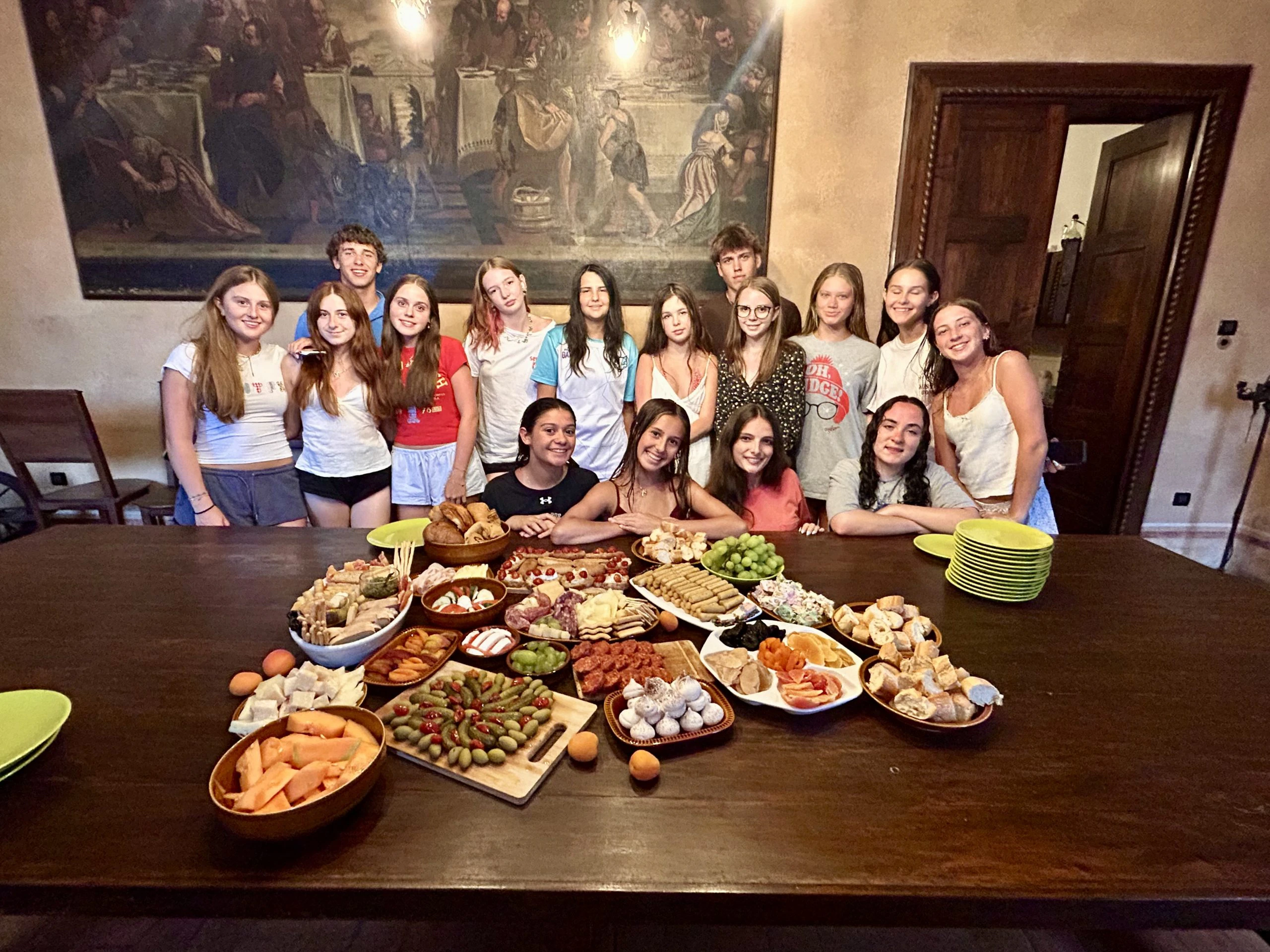 Students gather around a table spread with a large platter of appetizers and fruit