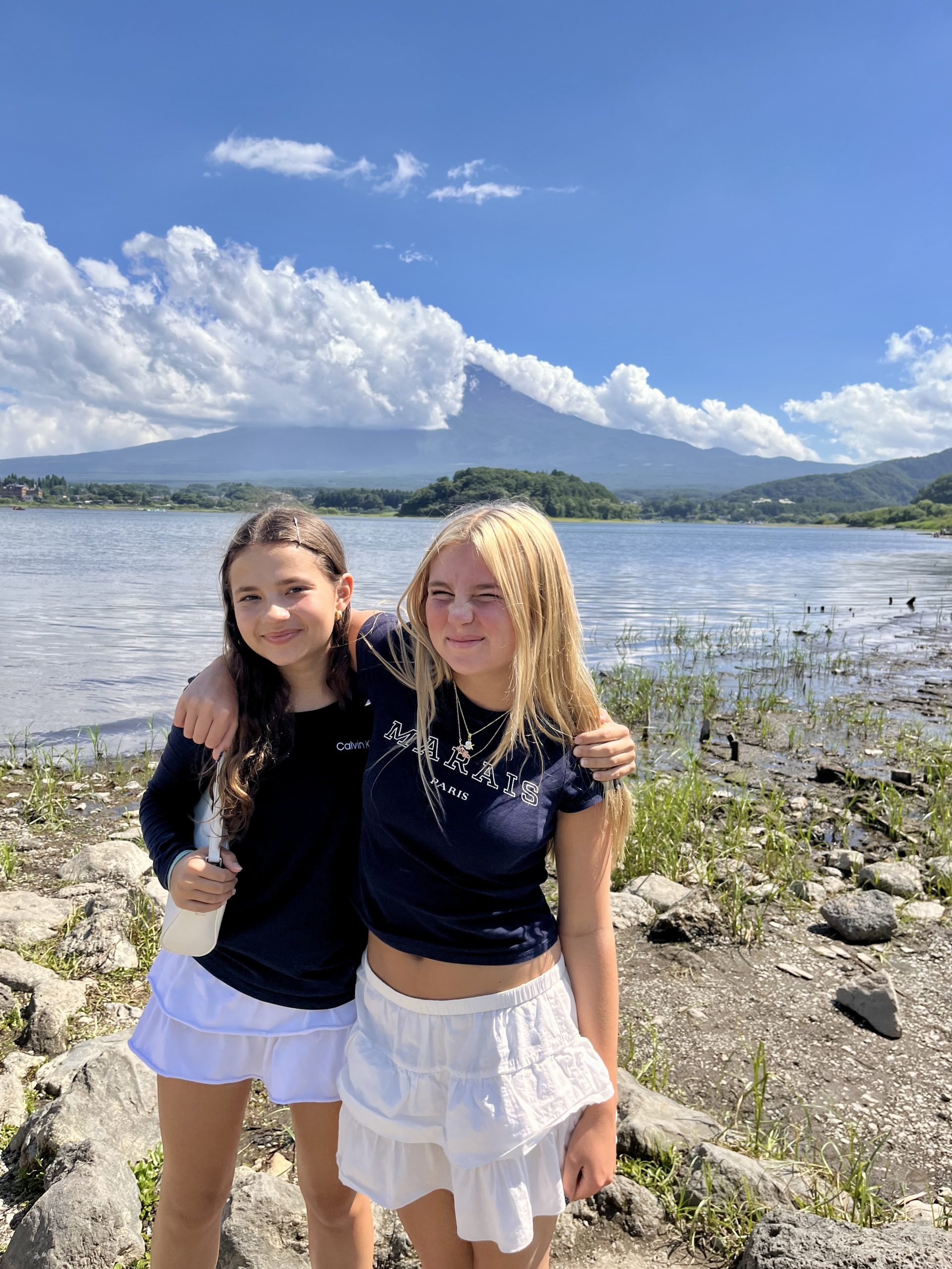 Students pose lakeside with a cloud-wreathed mountain in the background